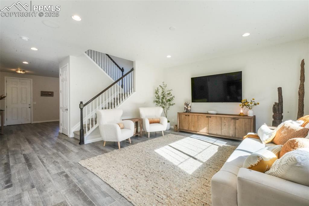 Image 10 of 50: Living area with wood finished floors, stairway, and recessed lighting