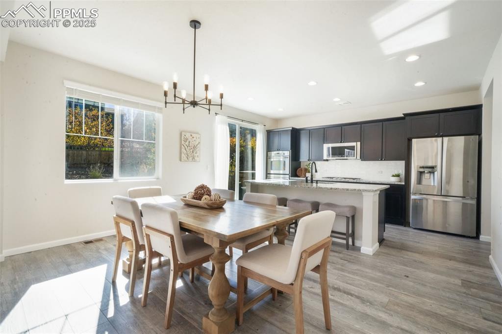 Image 12 of 50: Dining room with light wood-type flooring, a chandelier, and recessed light