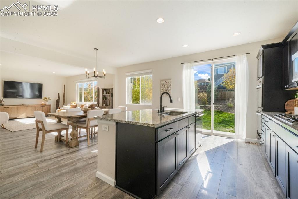 Image 15 of 50: Kitchen featuring light stone counters, hanging light fixtures, open floor