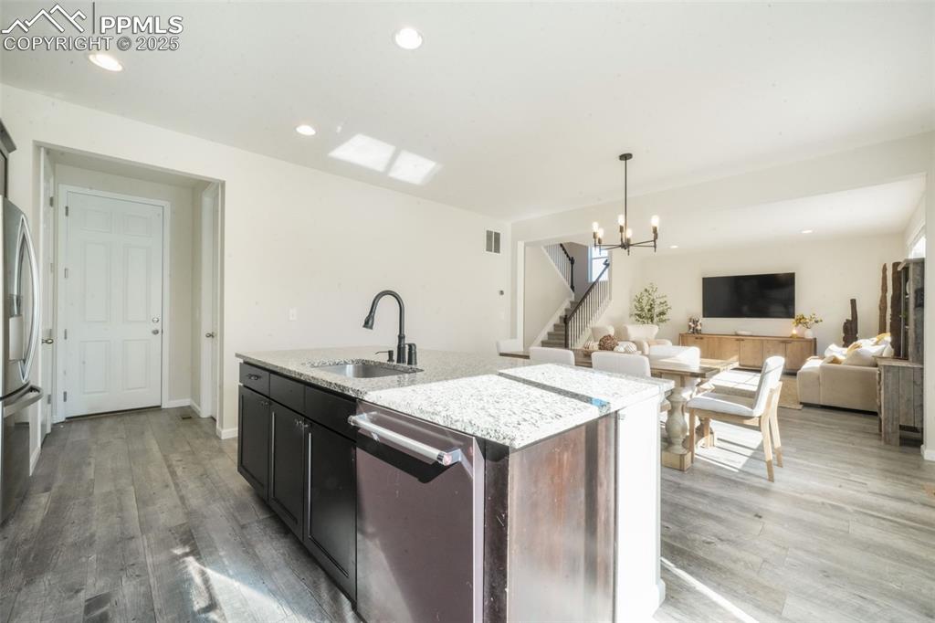 Image 16 of 50: Kitchen with recessed lighting, open floor plan, a chandelier, light stone