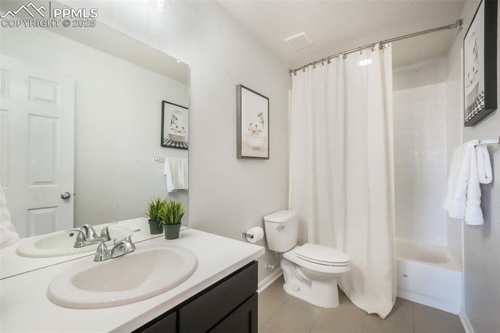 Image 23 of 50: Bathroom with light tile patterned floors, vanity, and shower / tub combo