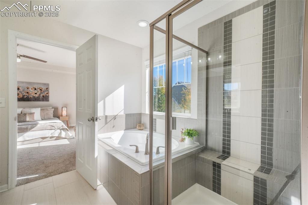 Image 30 of 50: Bathroom featuring connected bathroom, a garden tub, light colored carpet,