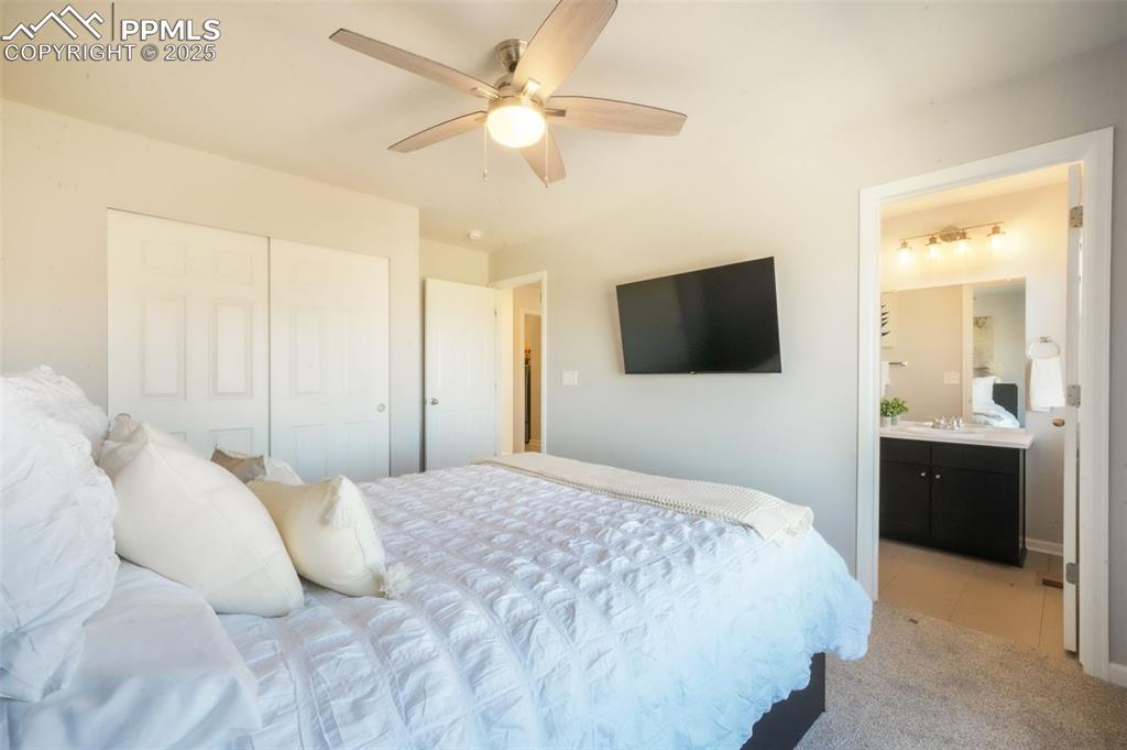 Image 32 of 50: Bedroom featuring light colored carpet, ceiling fan, a closet, and connecte