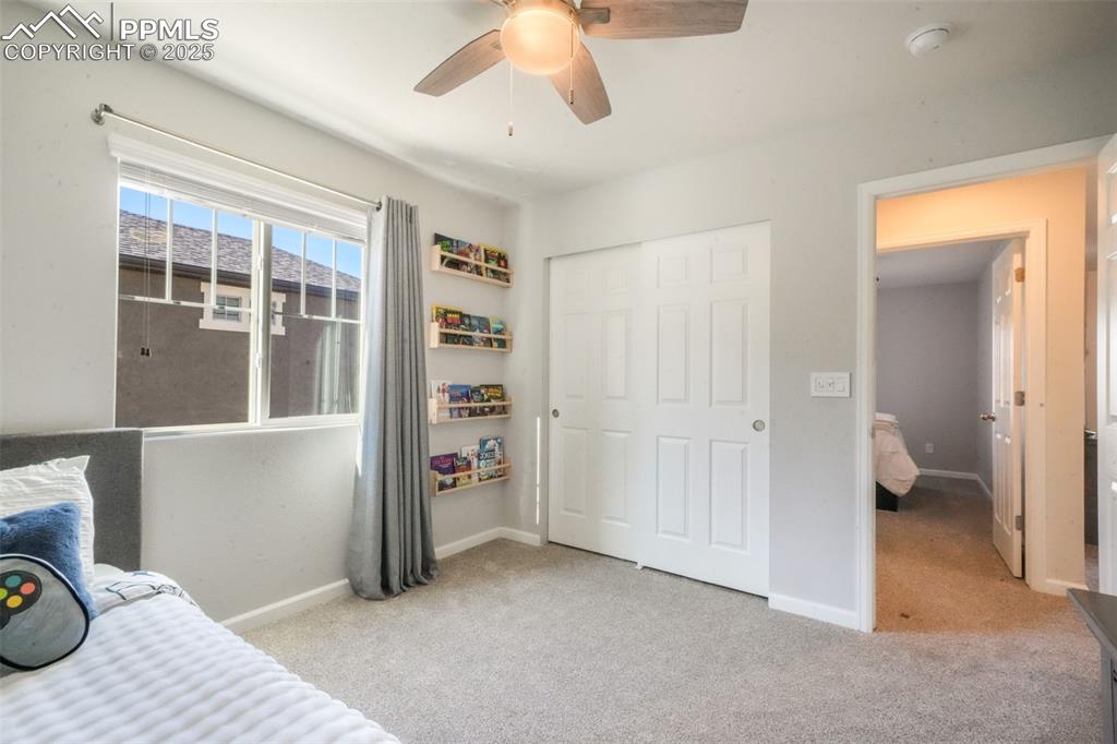 Image 38 of 50: Bedroom with light carpet, a closet, and a ceiling fan