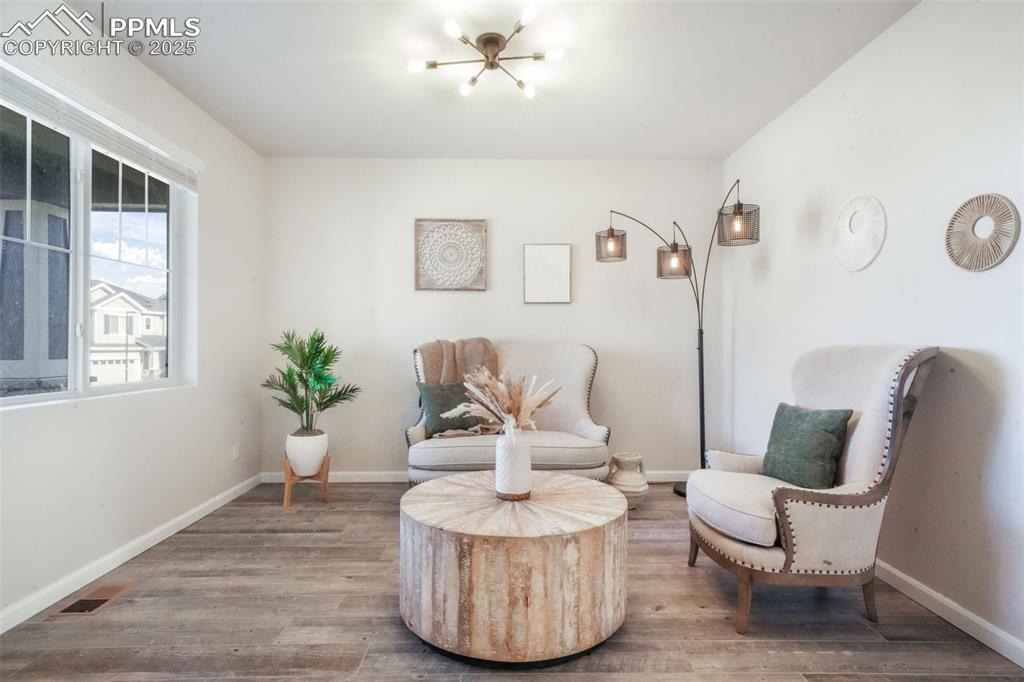 Image 4 of 50: Living area with baseboards and wood finished floors