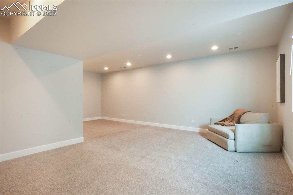 Image 46 of 50: Living area with recessed lighting and light colored carpet