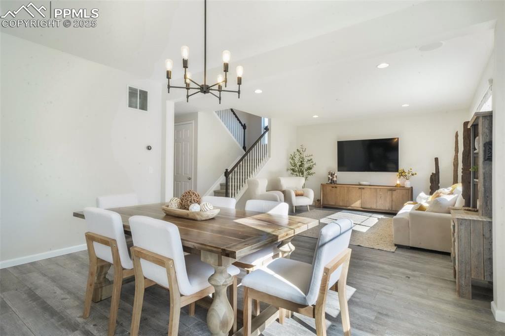 Image 7 of 50: Dining room with stairway, wood finished floors, a chandelier, and recessed