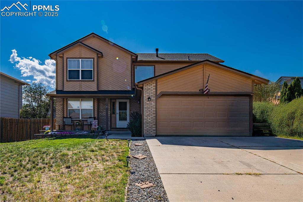 Caption: Warm-toned two-story family home with brick and wood siding, nestled beneath a clear blue sky. The d