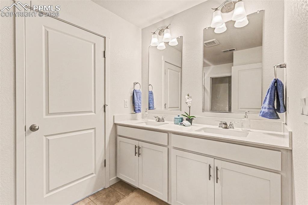 Image 12 of 22: Double vanity and walk-in shower in master bathroom. Quartz counters in all