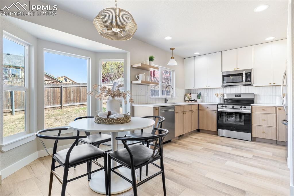 Image 10 of 26: Two tone kitchen with light countertops, stainless steel appliances, backsp