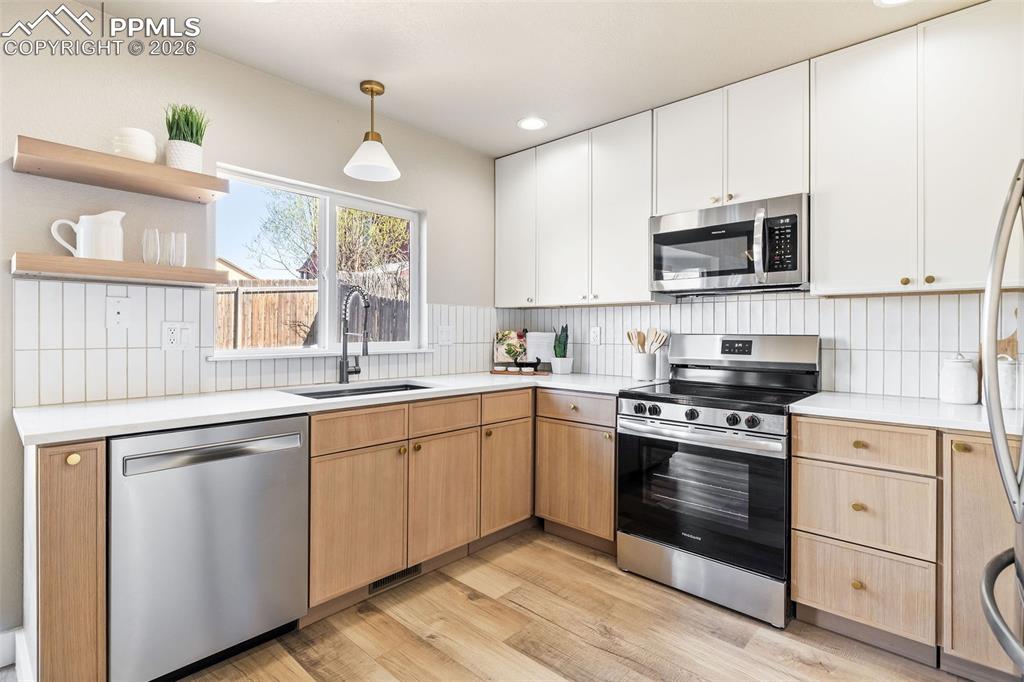 Image 12 of 26: Two tone kitchen featuring stainless steel appliances, open shelves, two to
