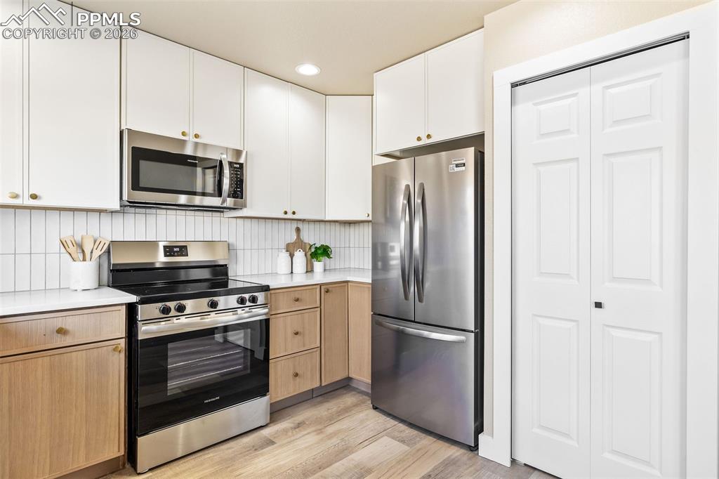 Image 13 of 26: Two tone kitchen featuring stainless steel appliances, light wood-style flo