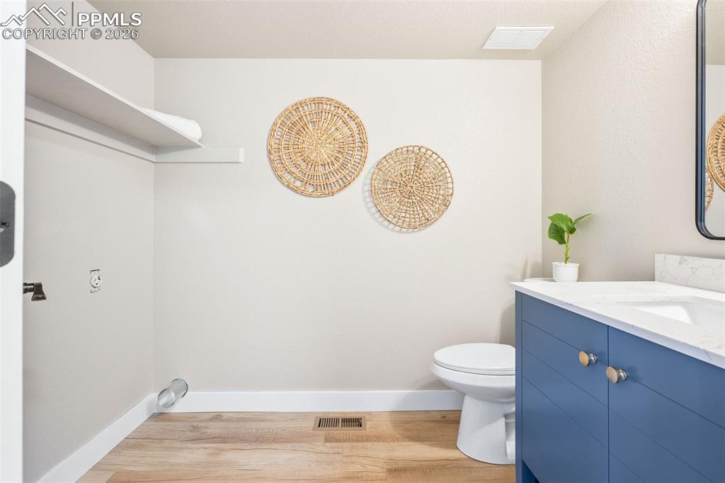 Image 15 of 26: Bathroom with vanity and light wood-style floors and laundry space 