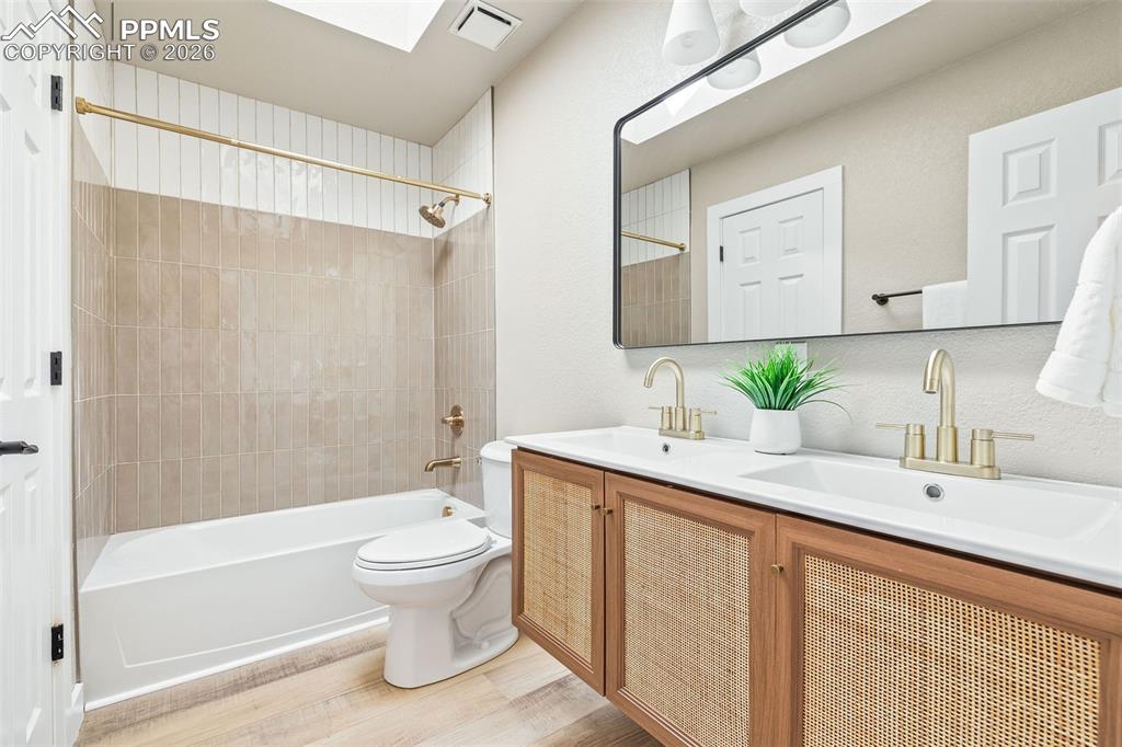 Image 19 of 26: Bathroom with double vanity, washtub / shower combination, and light wood-s