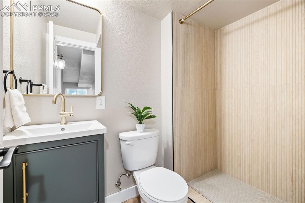 Image 25 of 26: Bathroom featuring vanity, walk in shower, and a textured wall