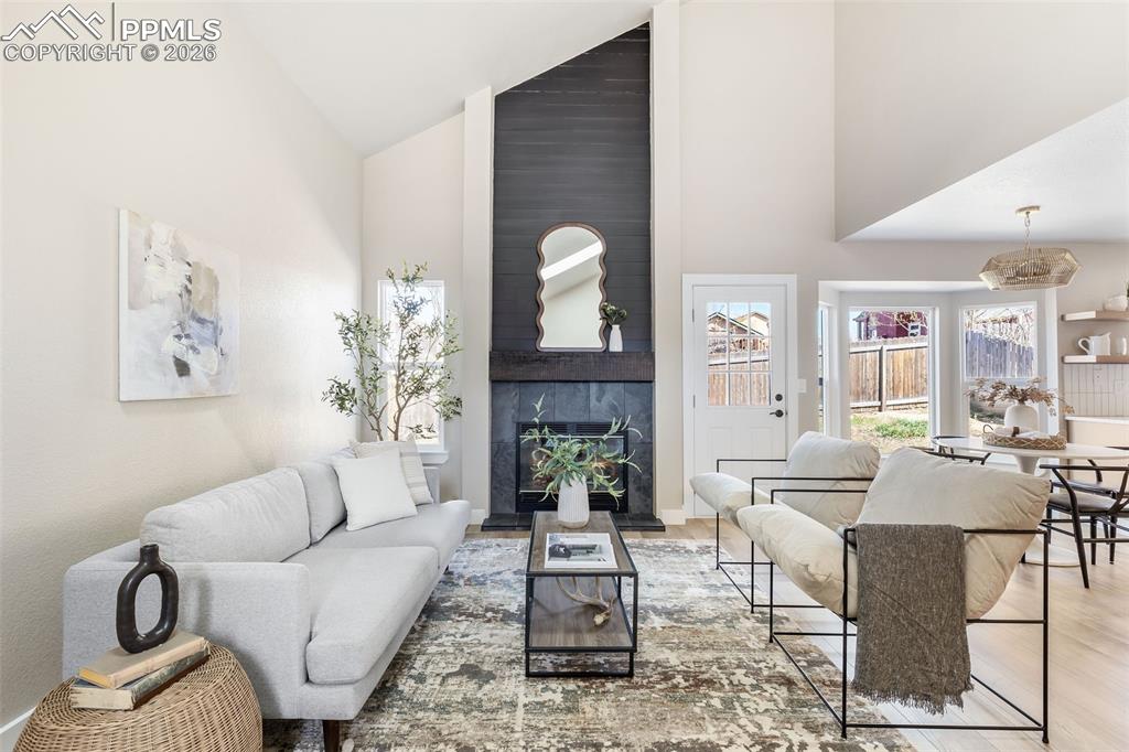 Image 5 of 26: Living room featuring a premium fireplace, lofted ceiling, and wood finishe