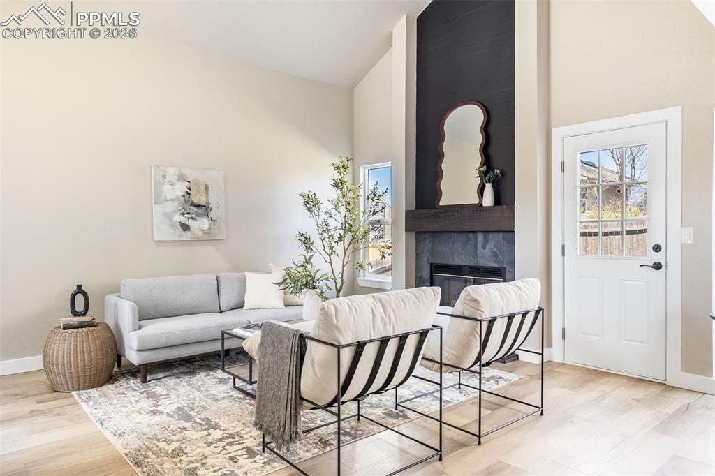 Image 8 of 26: Living room with vaulted ceiling, light wood-style floors, and a high end f