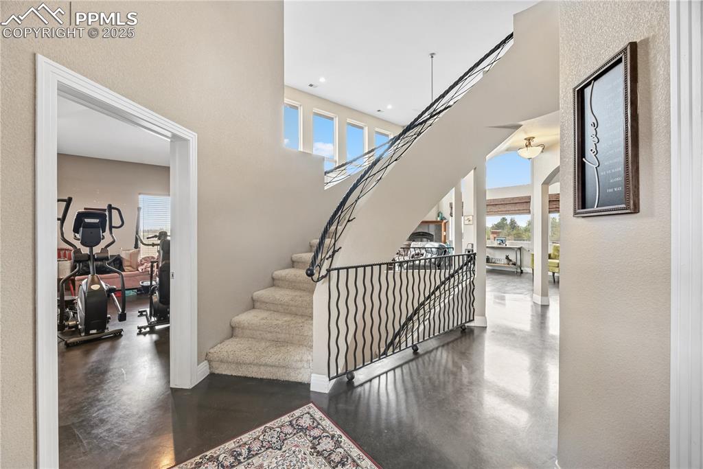 Image 11 of 40: Staircase with a high ceiling, finished concrete flooring, a textured wall,