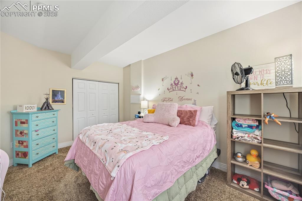 Image 18 of 40: Carpeted bedroom with beam ceiling and a closet