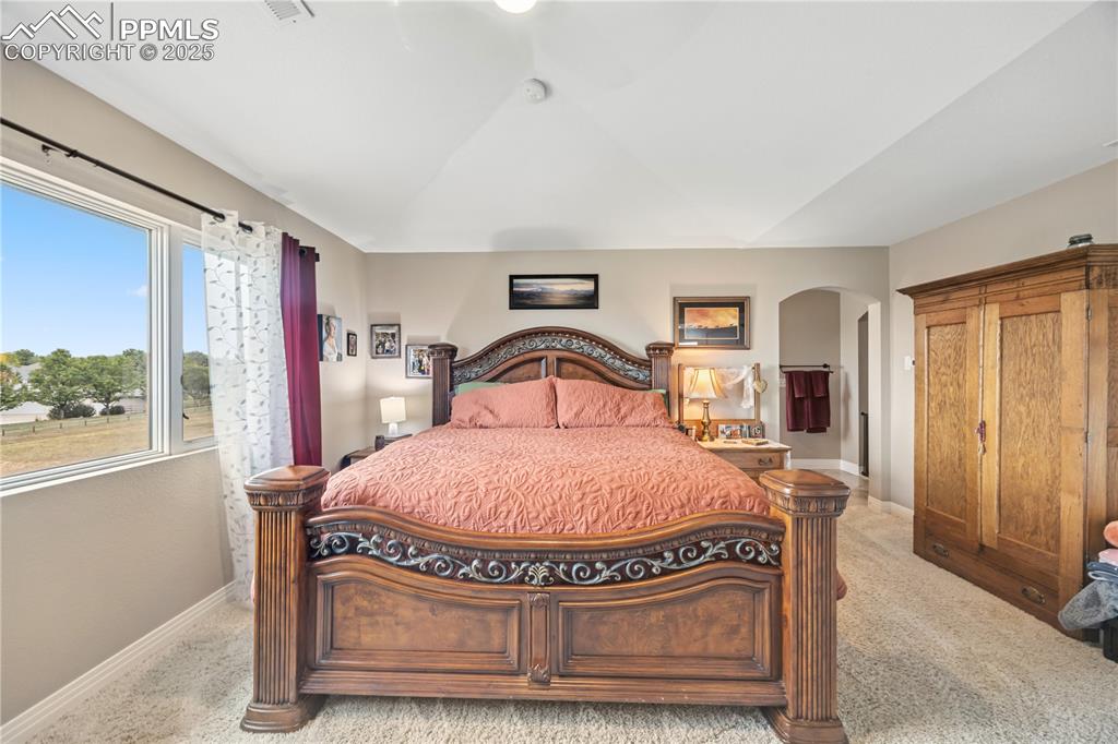 Image 24 of 40: Bedroom with light carpet, a ceiling fan, and arched walkways