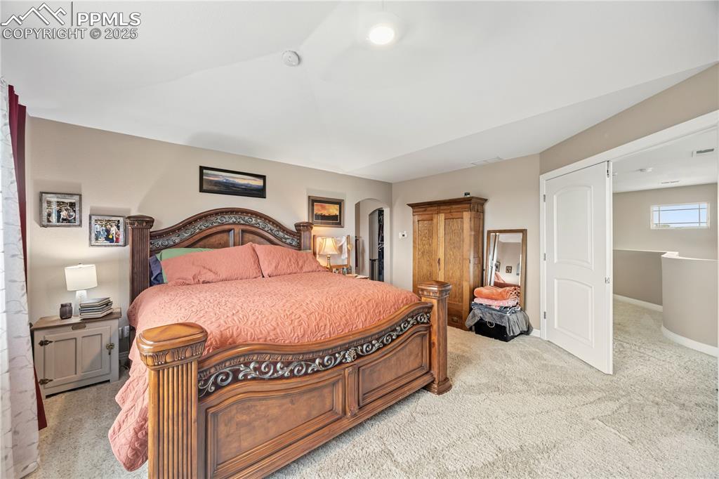 Image 25 of 40: Bedroom with carpet floors and arched walkways