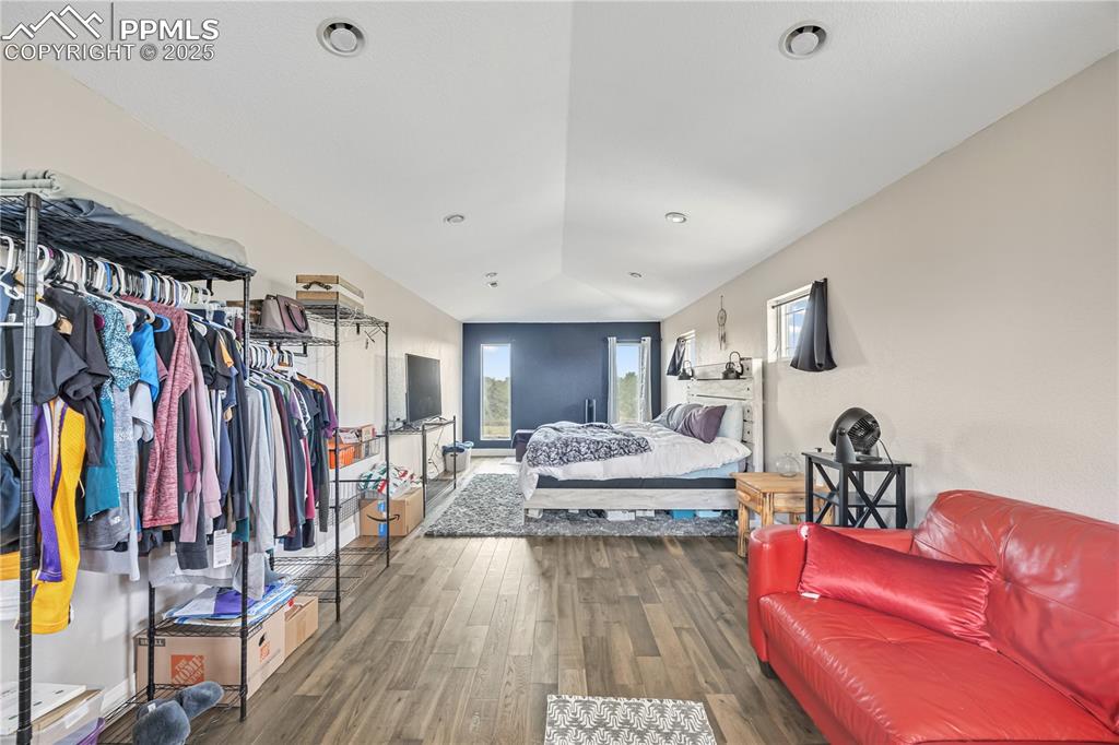 Image 29 of 40: Bedroom with dark wood-style flooring, lofted ceiling, and recessed lightin