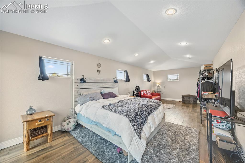 Image 31 of 40: Bedroom featuring wood finished floors, lofted ceiling, and recessed lighti