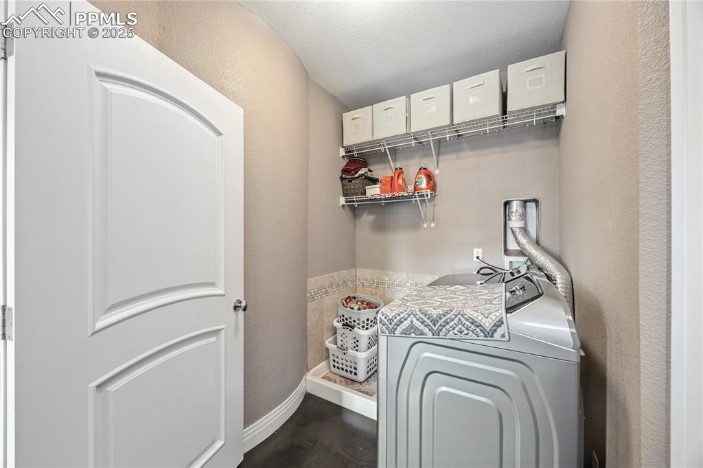 Image 32 of 40: Washroom featuring a textured wall, washer / clothes dryer, and a textured