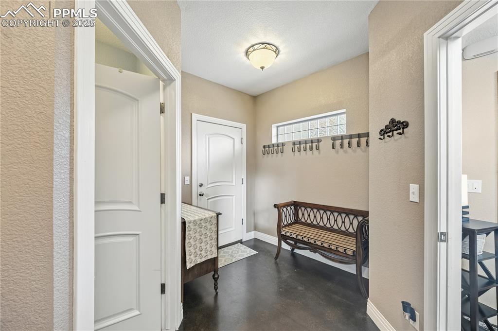 Image 33 of 40: Mudroom with concrete flooring, a textured wall, and a textured ceiling