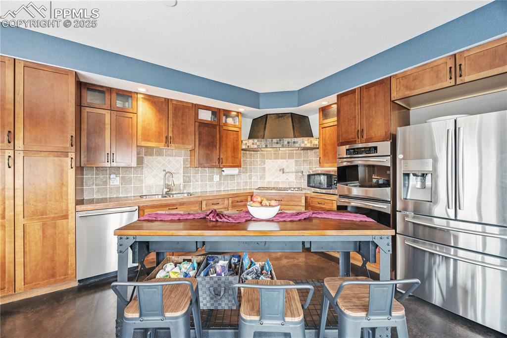 Image 9 of 40: Kitchen with appliances with stainless steel finishes, tasteful backsplash,