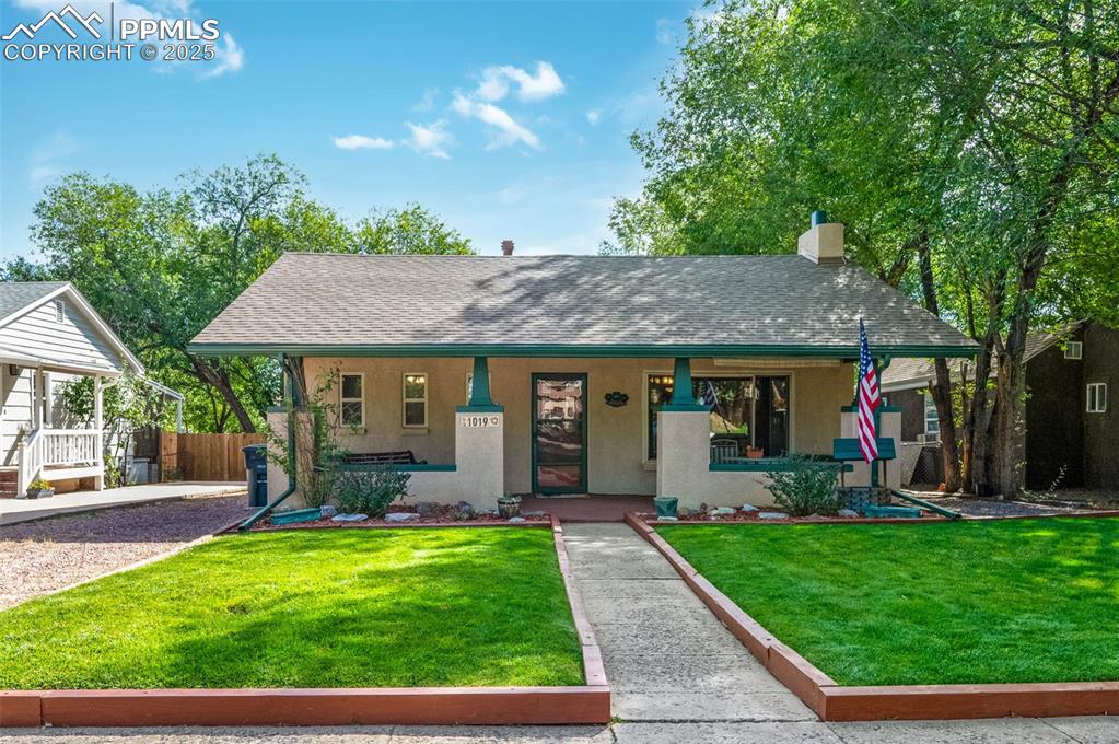 Caption: View of front of house with stucco siding, and covered front porch