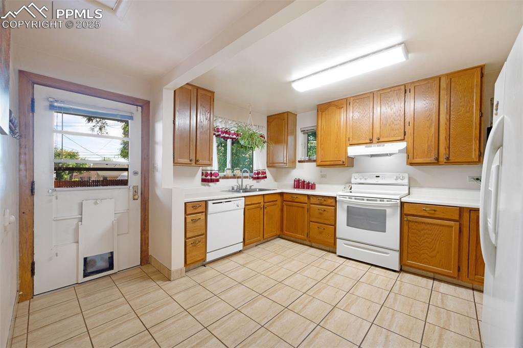Image 12 of 27: Kitchen with white appliances, light countertops, light tile patterned floo