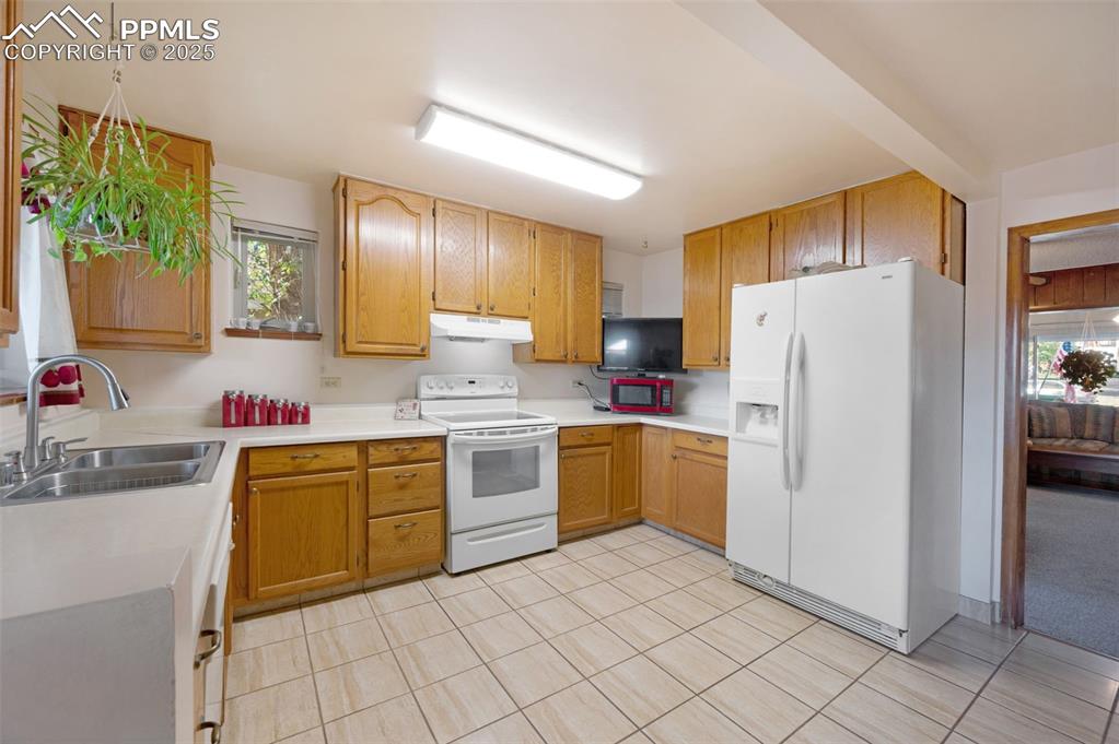 Image 13 of 27: Kitchen with light countertops, white appliances, light tile patterned floo
