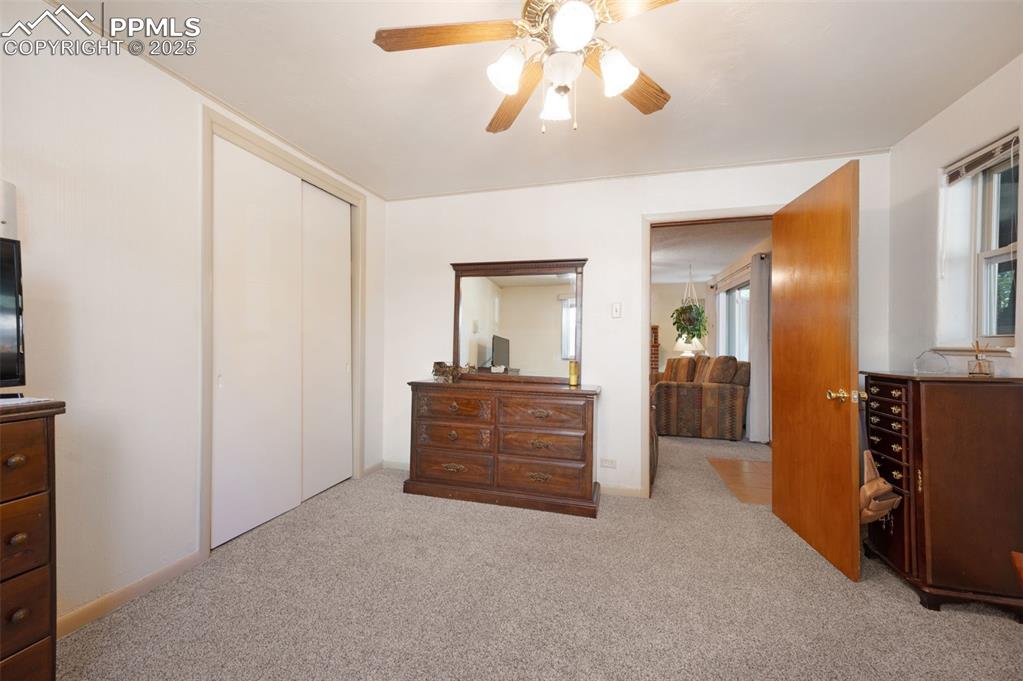 Image 15 of 27: Bedroom featuring light carpet, multiple windows, a ceiling fan, and a clos
