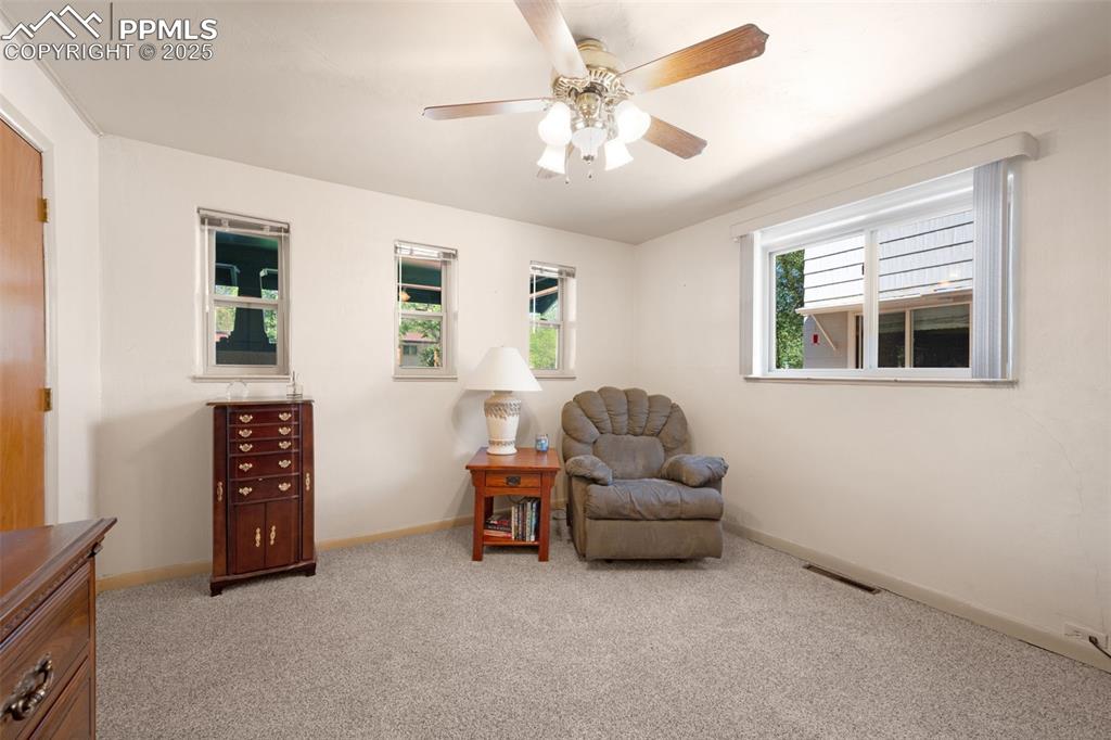 Image 16 of 27: Living area featuring light colored carpet and ceiling fan