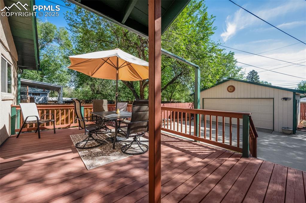 Image 22 of 27: Wooden terrace with an outdoor structure, outdoor dining space, and a garag
