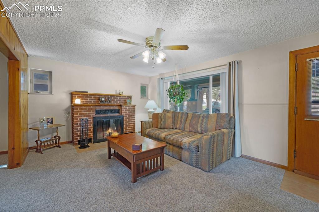 Image 7 of 27: Carpeted living room featuring a fireplace, a textured ceiling, and ceiling
