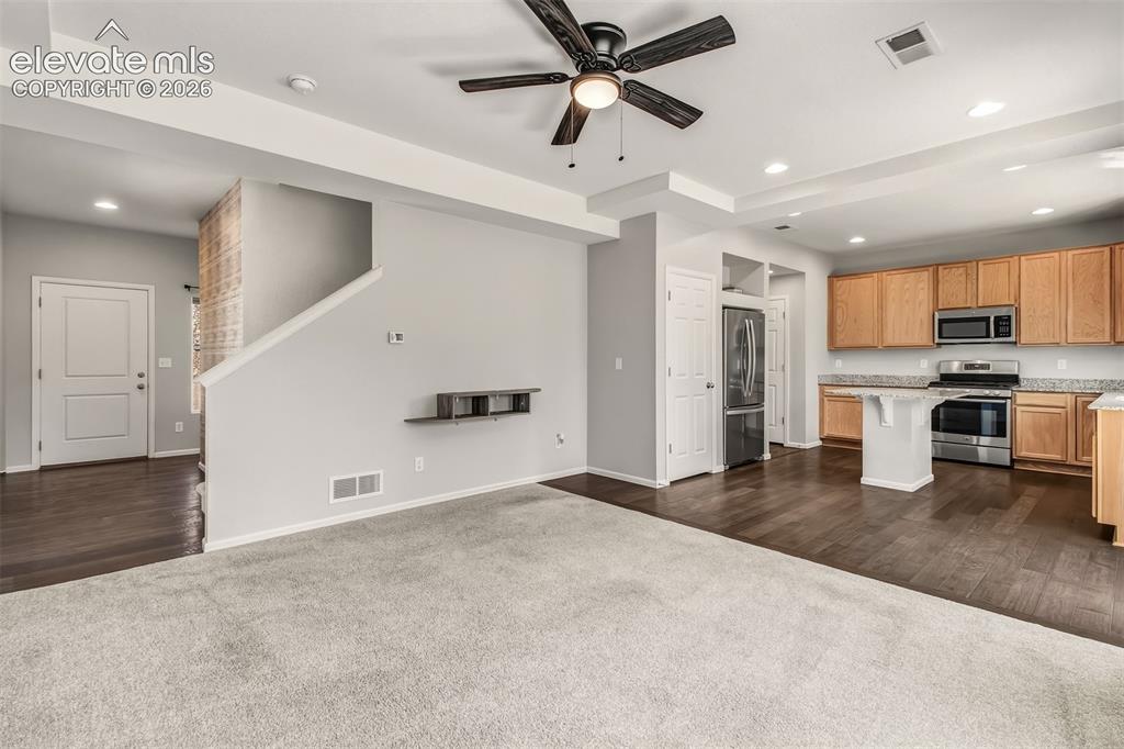 Image 9 of 41: Living room looking towards kitchen and foyer/stairway.