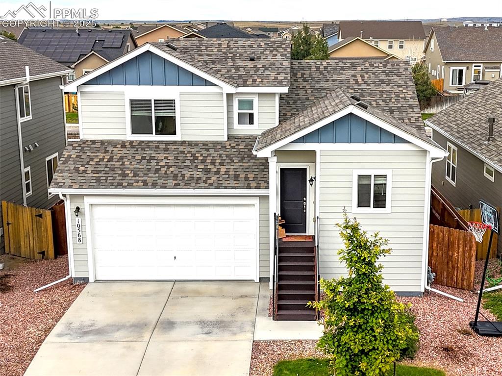 Caption: View of front of house with board and batten siding, roof with shingles, a residential view, and dri