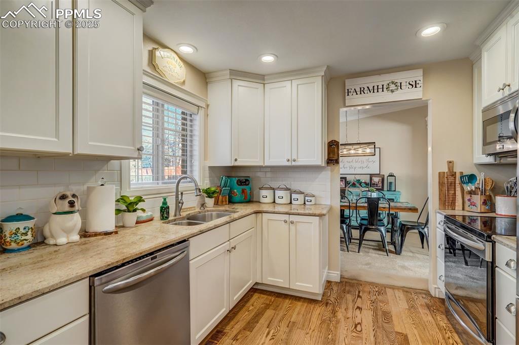 Image 14 of 50: Kitchen with a sink, white cabinets, appliances with stainless steel finish