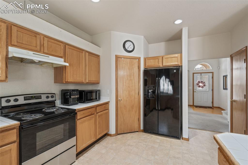 Image 12 of 40: Kitchen featuring wood cabinetry, a built-in oven with an electric cooktop,