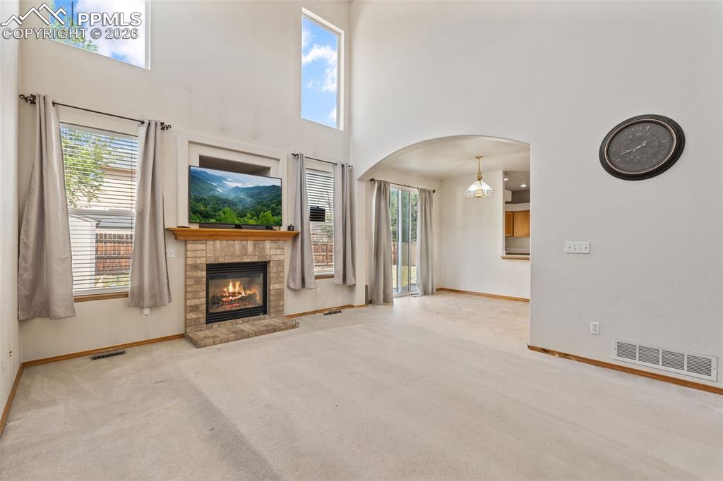 Image 16 of 40: Vaulted living area featuring a brick fireplace with a wood mantel, high wi