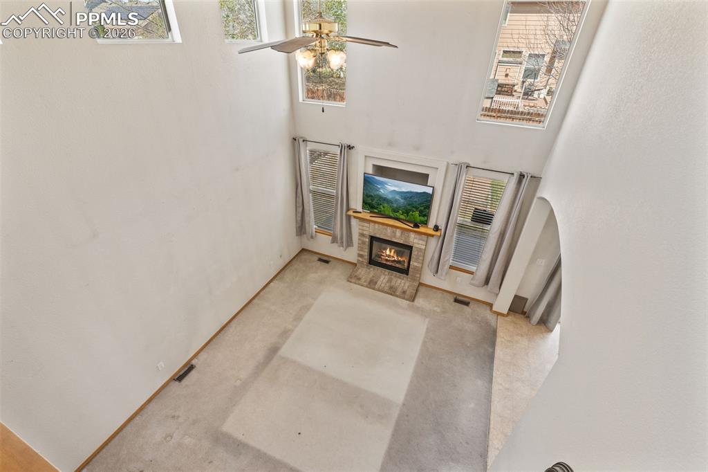 Image 20 of 40: Vaulted living area featuring a tiled fireplace with a wood mantel, multipl
