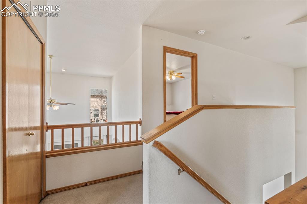 Image 21 of 40: Upper-level landing with wood-finish railing and trim, vaulted ceiling, and