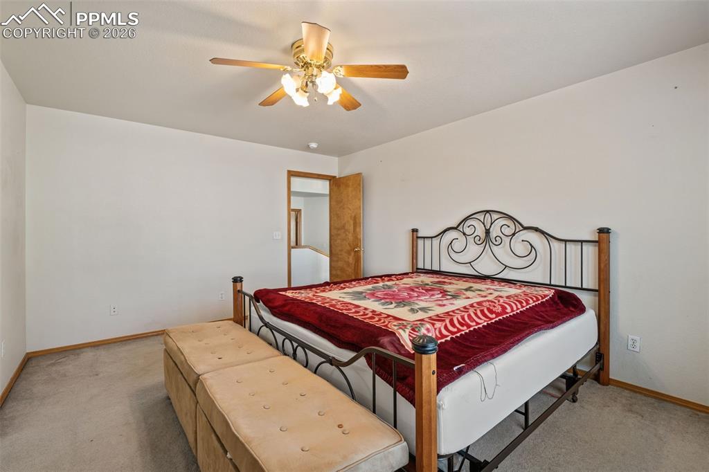 Image 24 of 40: Carpeted bedroom featuring a ceiling fan with light fixture and wood trim a