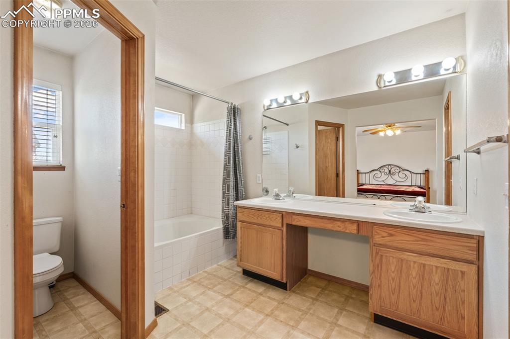 Image 26 of 40: Bathroom featuring dual vanity sinks set into a light-toned countertop, a l