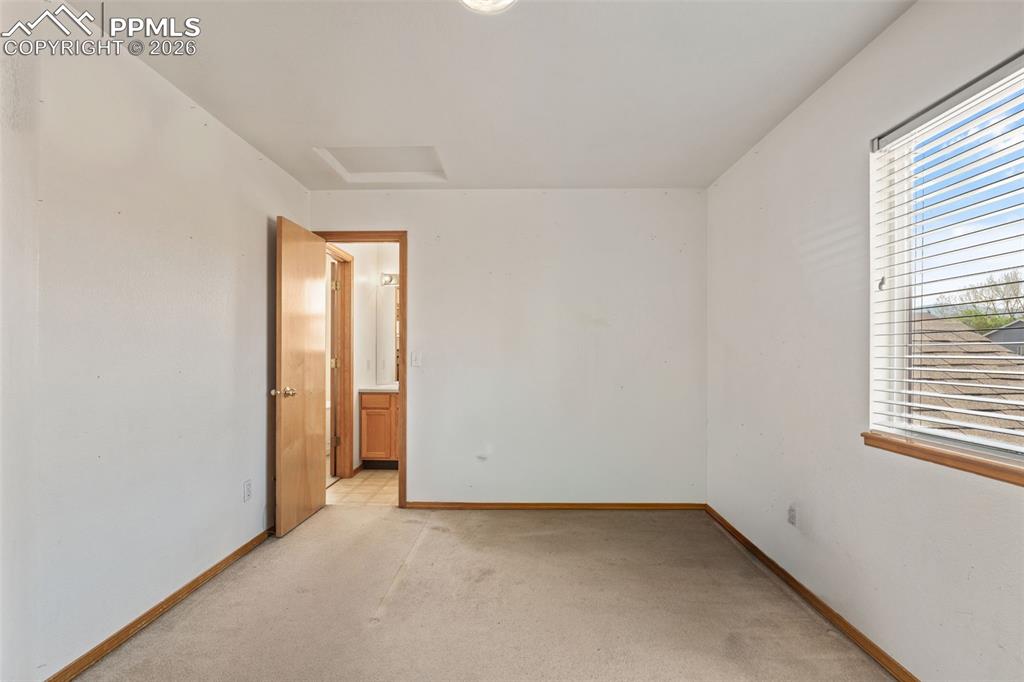 Image 27 of 40: Bedroom with neutral carpeting, white painted walls, and natural wood trim