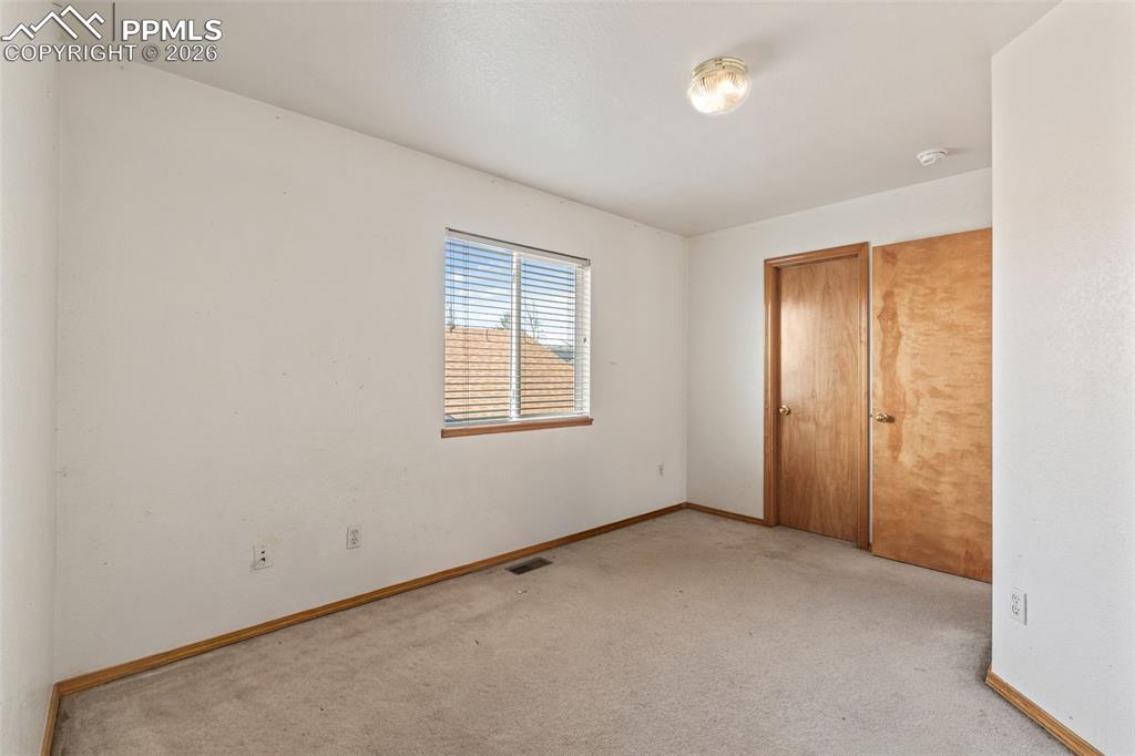 Image 28 of 40: Carpeted room featuring a window with horizontal blinds, wood trim, two woo