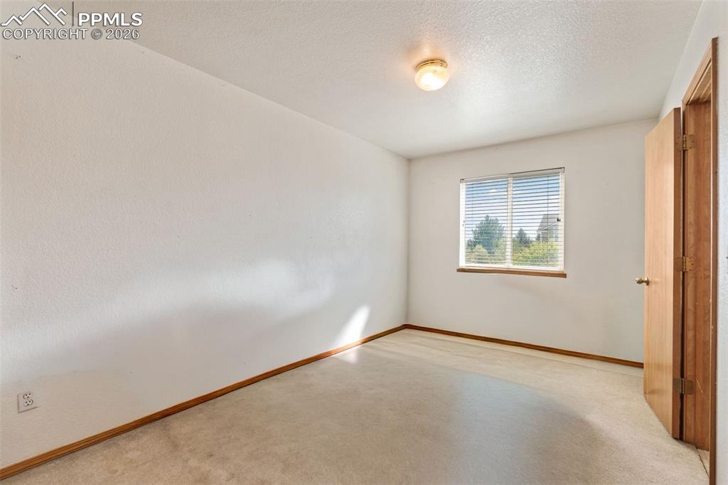 Image 30 of 40: Carpeted room featuring a single window with blinds, wood-finish trim, a fl