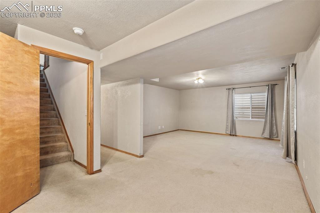 Image 31 of 40: Spacious carpeted room featuring a window with horizontal blinds, overhead 